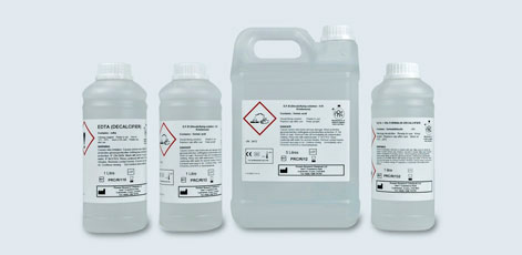 The image displays four containers of chemical substances. Three are smaller bottles, and one is a larger jug. Each container features hazard warning labels detailing safety information and usage instructions, indicating that they are potentially hazardous materials.