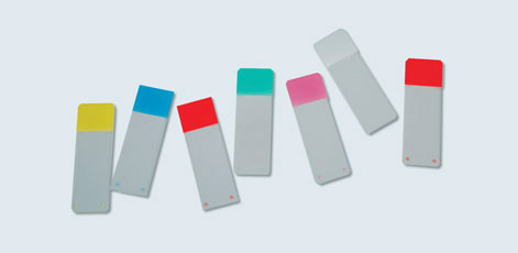 The image shows six rectangular sticky notes in various colors: yellow, blue, green, pink, and red. Each note has a white lower section, making them easily identifiable. They are arranged diagonally against a light background, emphasizing their vibrant colors.