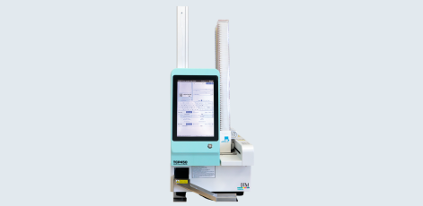 A medical imaging device is displayed, featuring a vertical configuration with a control panel on the front. The screen shows various data inputs and settings, and a vertical column extends upward, indicating a scanning function. The device is predominantly light blue and white.