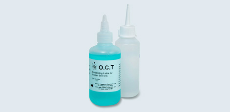Two bottles are shown; one is filled with a blue liquid labeled "O.C.T. Embedding Medium for Frozen Sections," while the other is a clear, empty squeeze bottle. The image highlights laboratory supplies used in histology.